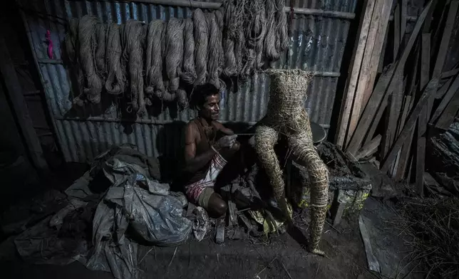 An artisan uses bamboo, hay and ropes to make a skeleton for the construction of a mud idol of the Hindu goddess Durga at a workshop during the Durga Puja festival in Guwahati, India, Friday, Oct. 4, 2024. (AP Photo/Anupam Nath)