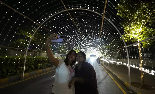 Girls takes selfie on an illuminated road on the Hindu festival of lights Diwali in Ahmedabad, India, Thursday, Oct. 31, 2024. (AP Photo/Ajit Solanki)