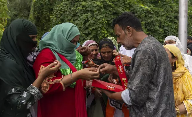 Kashmiri man distributes sweets among supporters of Indian National Congress and National Conference party as they celebrate early leads in the election for a local government in Indian controlled Kashmir, Srinagar, Tuesday, Oct. 8, 2024. (AP Photo/Dar Yasin)