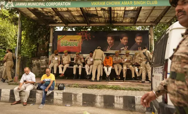 Security personnel take rest under a passenger shed outside a counting center in Jammu, India, Tuesday, Oct. 8, 2024. (AP Photo/Channi Anand)