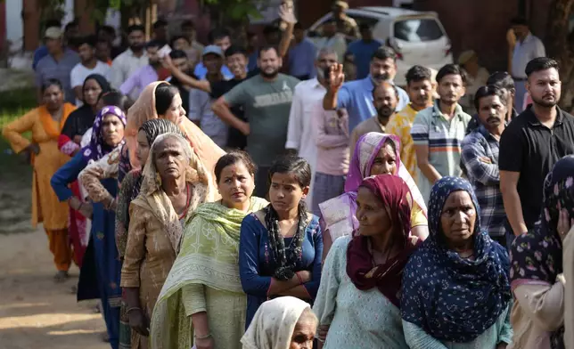 People queue up to cast their vote at a polling booth during the final phase of an election to choose a local government in Indian-controlled Kashmir, in Jammu, India, Tuesday, Oct.1, 2024. (AP Photos/Channi Anand)