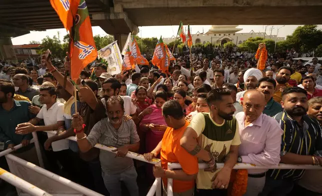 Bharatiya Janata Party (BJP) supporters hold party flags and wait outside a counting center in Jammu, India, Tuesday, Oct. 8, 2024. (AP Photo/Channi Anand)