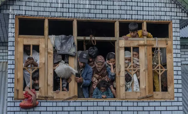 Kashmiri villagers watch from the window of a residential house the funeral of Mushtaq Ahmad, an army porter who was among those killed in a rebel ambush on an army vehicle on Thursday night, in Nowshera village north of Srinagar, Indian controlled Kashmir, Friday, Oct. 25, 2024. (AP Photo/Dar Yasin)