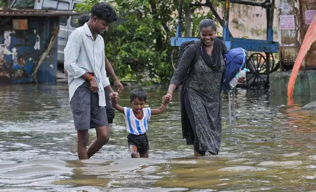 A family wades through a flooded street after heavy rains in Chennai, India, Wednesday, Oct.16, 2024. (AP Photo/Mahesh Kumar A.)