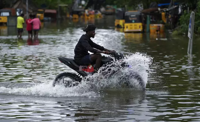 A motorcyclist wades through a flooded street after heavy rains in Chennai, India, Wednesday, Oct.16, 2024. (AP Photo/Mahesh Kumar A.)