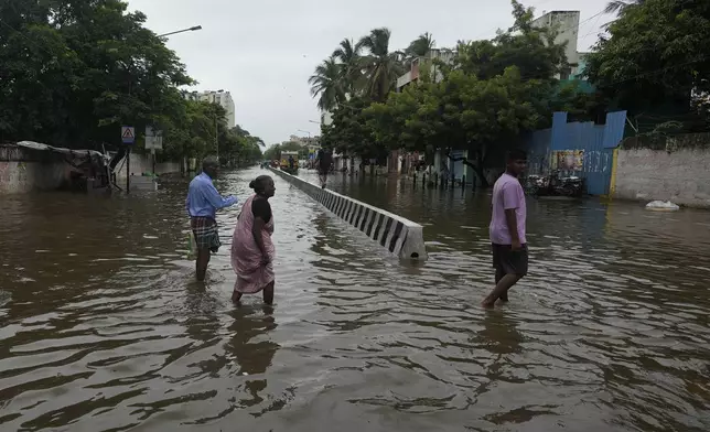 People wade through a flooded street after heavy rains in Chennai, India, Wednesday, Oct. 16, 2024. (AP Photo/Mahesh Kumar A.)
