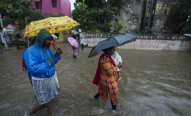 People wade through a flooded street after heavy rains in Chennai, India, Wednesday, Oct.16, 2024. (AP Photo/Mahesh Kumar A.)