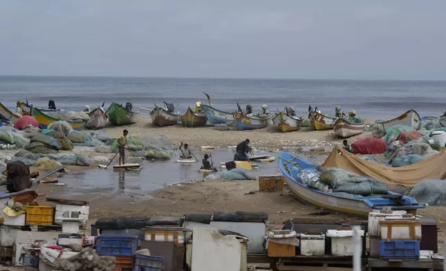 Fishermen children playing in water near the parked boats after heavy rains at Marina beach in Chennai, India, Wednesday, Oct. 16, 2024. (AP Photo/Mahesh Kumar A.)
