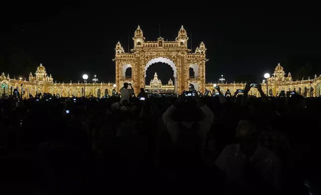 Visitors watch illuminated Amba Palace, a major tourist attraction, as part of the celebrations on the eve of final day of the Dussehra festivities, in Mysuru, India, Friday, Oct. 11, 2024. (AP Photo/Aijaz Rahi)