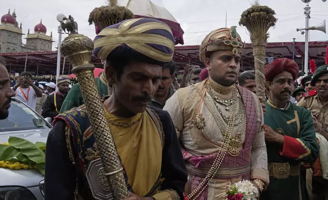 Yaduveer Krishnadatta Chamaraja Wadiyar, center, the titular head of the Wadiyar dynasty, walks with his aides to participate in prayers ahead of a procession on the last day of the Dussehra festivities, in Mysuru, India, Saturday, Oct. 12, 2024. (AP Photo/Aijaz Rahi)