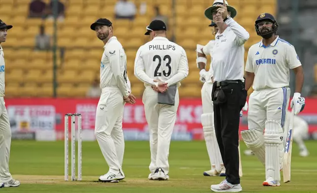 Umpire Paul Reiffel points skywards as players wait for the play to start on the day two of the first cricket test match between India and New Zealand at the M.Chinnaswamy Stadium, in Bengaluru, India, Thursday, Oct. 17, 2024. (AP Photo/Aijaz Rahi)