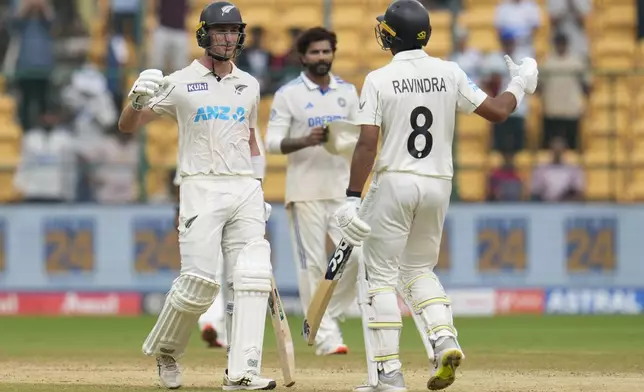 New Zealand's Will Young, left, and Rachin Ravindra celebrate after their win against India on the day five of the first cricket test match at the M.Chinnaswamy Stadium, in Bengaluru, India, Sunday, Oct. 20, 2024. (AP Photo/Aijaz Rahi)