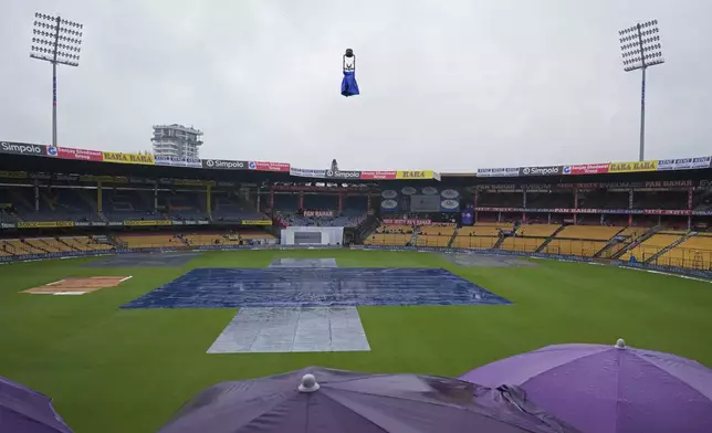 The pitch area is covered with plastic sheets after rains delayed the start of the day one of the first cricket test match between India and New Zealand at the M.Chinnaswamy Stadium, in Bengaluru, India, Wednesday, Oct. 16, 2024. (AP Photo/Aijaz Rahi)