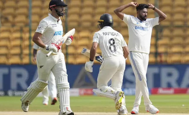 New Zealand's Daryl Mitchell, left, and Rachin Ravindra run between the wickets to score during the day three of the first cricket test match between India and New Zealand at the M.Chinnaswamy Stadium, in Bengaluru, India, Friday, Oct. 18, 2024. (AP Photo/Aijaz Rahi)