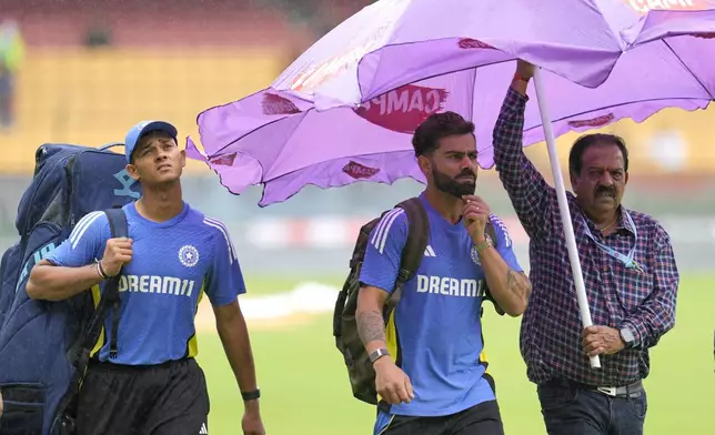 India's Virat Kohli, center, and Yashasvi Jaiswal, left, walk across the field after rains delayed the start of the day one of the first cricket test match between India and New Zealand at the M.Chinnaswamy Stadium, in Bengaluru, India, Wednesday, Oct. 16, 2024. (AP Photo/Aijaz Rahi)