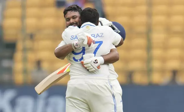 India's Rishabh Pant, facing camera, hugs batting partner Sarfaraz Khan to congratulate him on scoring a century during the day four of the first cricket test match between India and New Zealand at the M.Chinnaswamy Stadium, in Bengaluru, India, Saturday, Oct. 19, 2024. (AP Photo/Aijaz Rahi)