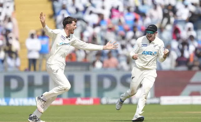 New Zealand's Mitchell Santner, left, and New Zealand's captain Tom Latham celebrates the dismissal of India's Virat Kohli during the day three of the second cricket test match between India and New Zealand at the Maharashtra Cricket Association Stadium , in Pune, India, Saturday, Oct. 26, 2024. (AP Photo/Rafiq Maqbool)