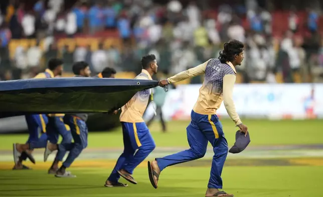 Groundsmen pull on the covers after rain stopped play on the day four of the first cricket test match between India and New Zealand at the M.Chinnaswamy Stadium, in Bengaluru, India, Saturday, Oct. 19, 2024. (AP Photo/Aijaz Rahi)