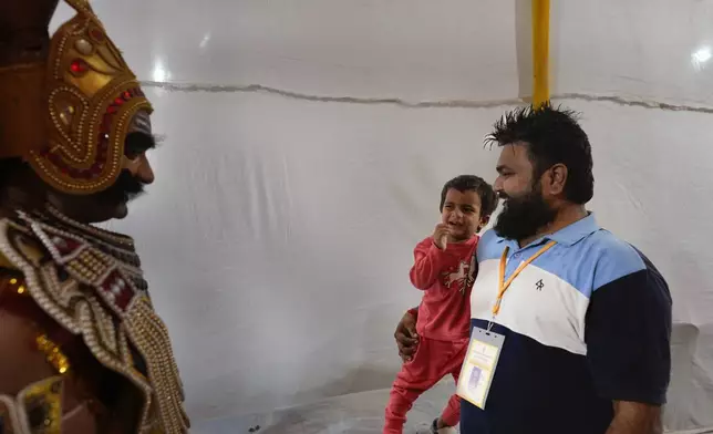 A child reacts as Vikas Sirswal, 32, playing the character of the demon king Ravana, walks past after performing in Ramleela, a dramatic folk re-enactment of the life of Hindu god Rama according to the ancient Hindu epic Ramayana, in New Delhi, India, Wednesday, Oct. 9, 2024. (AP Photo/Manish Swarup)