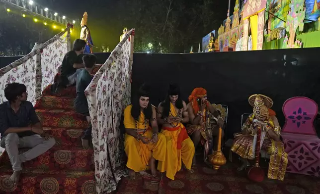 Ashutosh Agnihotri, 23, playing the character of Hindu god Rama, sitting to the right of the partition, waits with others to go onstage during Ramleela, a dramatic folk re-enactment of the life of Rama according to the ancient Hindu epic Ramayana, in New Delhi, India, Thursday, Oct. 10, 2024. (AP Photo/Manish Swarup)