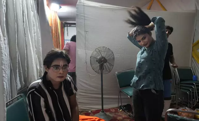 Ashutosh Agnihotri, 23, playing the character of Hindu god Rama, left, rests backstage as Hitanshi Jha, 21, playing the character of Sita, ties her hair at the end of the third day of Ramleela, a dramatic folk re-enactment of the life of Rama according to the ancient Hindu epic Ramayana, in New Delhi, India, Wednesday, Oct. 9, 2024. (AP Photo/Manish Swarup)