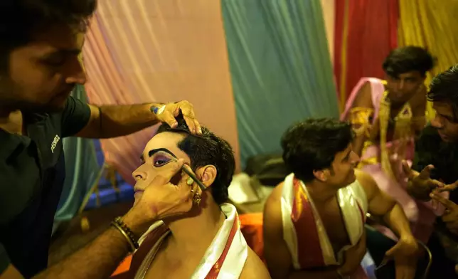 A makeup artist gets an actor ready backstage before the start of Ramleela, a dramatic folk re-enactment of the life of Hindu god Rama according to the ancient Hindu epic Ramayana, in New Delhi, India, Saturday, Oct. 5, 2024. (AP Photo/Manish Swarup)