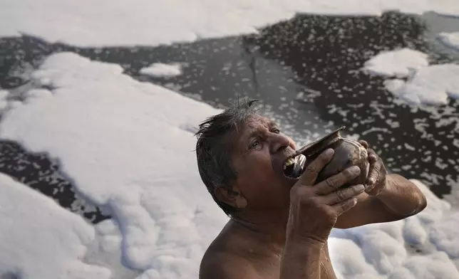 Jasraj, 70, drinks water from the river Yamuna filled with toxic foams in New Delhi, India, Tuesday, Oct. 29, 2024. (AP Photo/Manish Swarup)