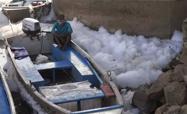 A worker for the Delhi Jal or water board sits in his boat in the river Yamuna filled with toxic foams in New Delhi, India, Tuesday, Oct. 29, 2024. (AP Photo/Manish Swarup)