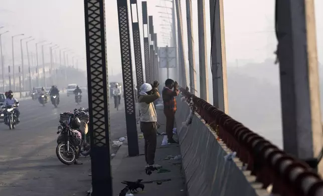 Commuters pray from a bridge across the river Yamuna in New Delhi, India, Tuesday, Oct. 29, 2024. (AP Photo/Manish Swarup)