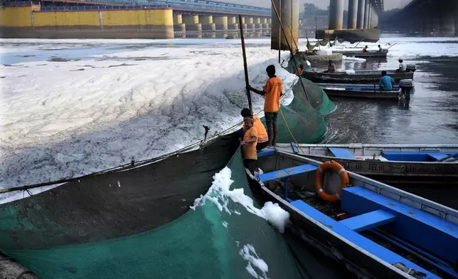 Workers for the Delhi Jal or water board put up a cloth curtain to stop the flow of the toxic foams floating in the river Yamuna in New Delhi, India, Tuesday, Oct. 29, 2024. (AP Photo/Manish Swarup)