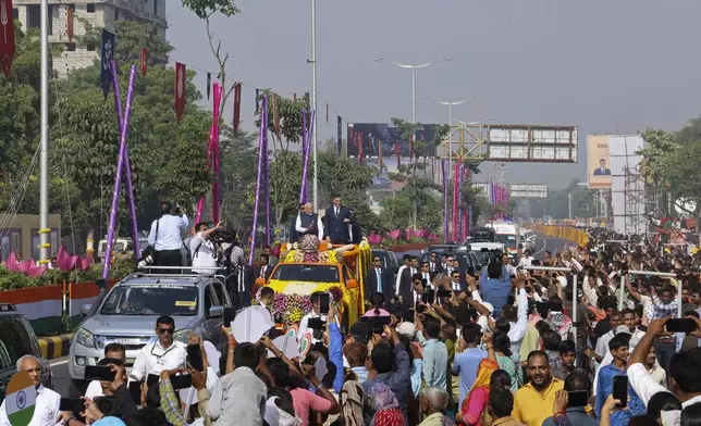 Indian Prime Minister Narendra Modi, center left, and his Spanish counterpart Pedro Sanchez, center right, wave to greet people from a vehicle in Vadodara, India, Monday, Oct. 28, 2024. (AP Photo)