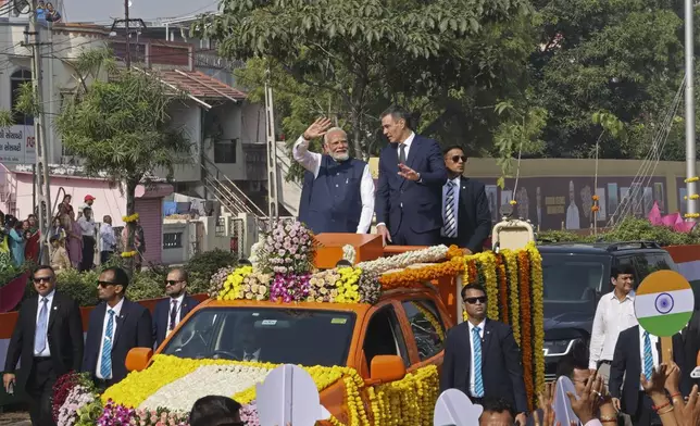 Indian Prime Minister Narendra Modi, center left, and his Spanish counterpart Pedro Sanchez, center right, wave to greet people from a vehicle in Vadodara, India, Monday, Oct. 28, 2024. (AP Photo)