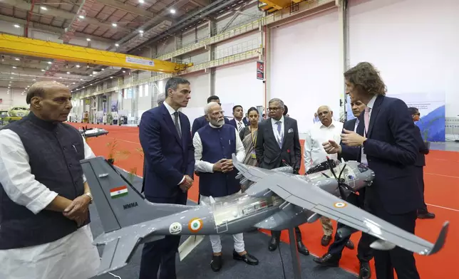 In this handout photo provided by the Press Information Bureau, Indian Prime Minister Narendra Modi, third left, and his Spanish counterpart Pedro Sanchez, second left, listen to an aide at the exhibition after inaugurating India's first private military aircraft plant in Vadodara, India, Monday, Oct. 28, 2024. (Press Information Bureau via AP)