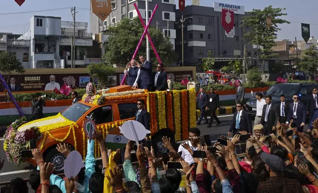 Indian Prime Minister Narendra Modi, center left, and his Spanish counterpart Pedro Sanchez, center right, wave to greet people from a vehicle in Vadodara, India, Monday, Oct. 28, 2024. (AP Photo)