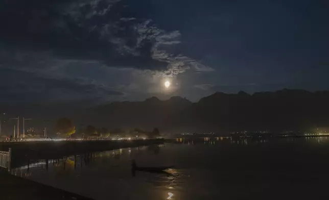 A supermoon rises behind the Zabarwan hills as a Kashmiri boatman rows his shikara at the Dal Lake on the outskirts of Srinagar, Indian controlled Kashmir, Thursday, Oct. 17, 2024. (AP Photo/Dar Yasin)