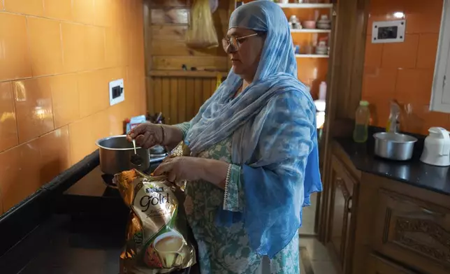 Firdosa Jan, a Kashmiri, pours Tata tea leaf into a container as she prepares tea in her kitchen on the outskirts of Srinagar, Indian controlled Kashmir, Thursday, Oct. 10, 2024. (AP Photo/Dar Yasin)