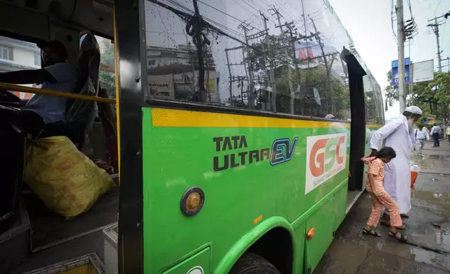 An elderly person gets down with a child from a Tata EV passenger bus in Guwahati, India, Thursday, Oct. 10, 2024. (AP Photo/Anupam Nath)