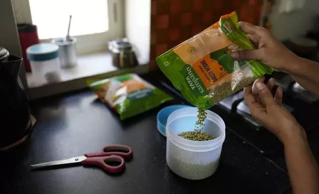 A woman fills a container with Tara lentils in her residence in New Delhi,India, Thursday, Oct. 10, 2024. (AP Photo/Manish Swarup)