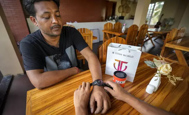 A man gifts a Tata made Titan sports watch to his friend in Guwahati, India, Thursday, Oct. 10, 2024. (AP Photo/Anupam Nath)