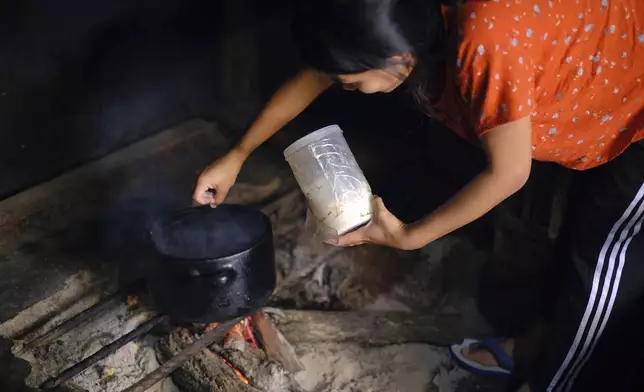 Teisovinuo Yhome, 25, adds Tata salt, stored in a separate container, to a dish cooked on an open fire in Kohima, capital of the northeastern Indian state of Nagaland, Thursday, Oct. 10, 2024. (AP Photo/Yirmiyan Arthur)