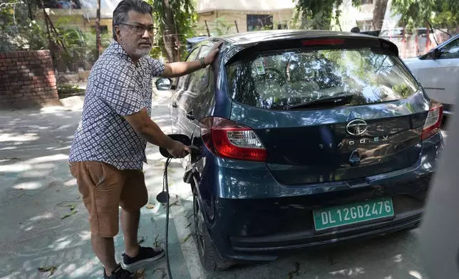 Prabhat Chandola charges his Tata electric vehicle in New Delhi, India, Thursday, Oct. 10, 2024. (AP Photo/Manish Swarup)