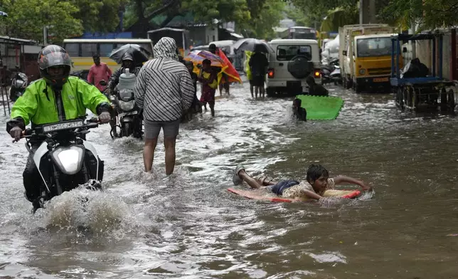 People wade through a flooded street during heavy rain in Chennai, India, Tuesday, Oct.15, 2024. (AP Photo/Mahesh Kumar A.)