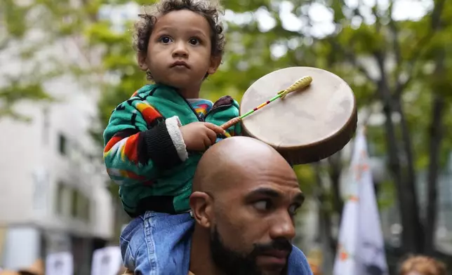 FILE - Khalako Lloyd, 2, of the Mandan and Hidatsa tribes, beats on a drum while carried on the shoulder of his father, Julius Lloyd during a celebratory march for Indigenous Peoples Day, Oct. 9, 2023, in Seattle. (AP Photo/Lindsey Wasson, File)