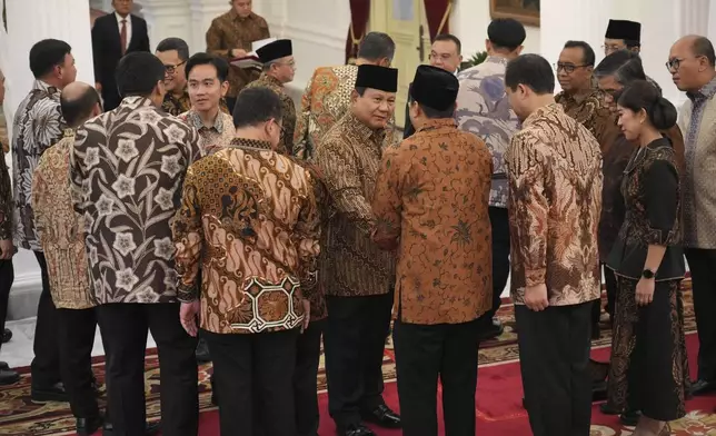 Indonesia's new President Prabowo Subianto, center, and Vice President Gibran Rakabuming Raka, left, shake hands with newly-appointed ministers after announcing their cabinet lineup at Merdeka Palace in Jakarta, Indonesia, Sunday, Oct. 20, 2024. (AP Photo/Achmad Ibrahim)