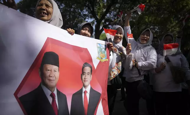 Indonesian supporters waves Indonesia flag and hold banner show Indonesian president-elect Prabowo Subianto, left, and vice president-elect Gibran Rakabuming Raka, who is also the eldest son of outgoing President Joko Widodo in Jakarta, Indonesia, Sunday, Oct. 20, 2024. (AP Photo/Dita Alangkara)