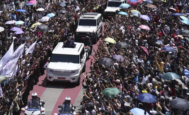 Newly-inaugurated Indonesian President Prabowo Subianto, center left in a vehicle, greets supporters after being sworn in as the country's eighth president in Jakarta, Indonesia, Sunday, Oct. 20, 2024. (AP Photo/Dita Alangkara)