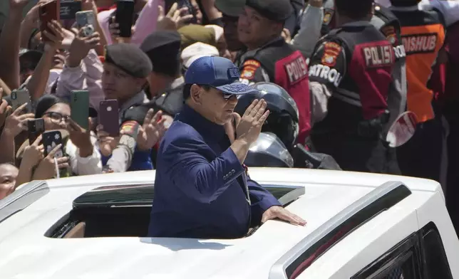 Newly-inaugurated Indonesian President Prabowo Subianto, center, salutes as he greets supporters after being sworn in as the country's eighth president in Jakarta, Indonesia, Sunday, Oct. 20, 2024. (AP Photo/Dita Alangkara)