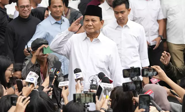 FILE - Indonesian Defense Minister and president-elect Prabowo Subianto, center, salutes to journalists in front of his running mate Gibran Rakabuming Raka, rear center, the eldest son of Indonesian President Joko Widodo, during their formal declaration as president and vice president-elect at the General Election Commission building in Jakarta, Indonesia, Wednesday, April 24, 2024. (AP Photo/Achmad Ibrahim, File)