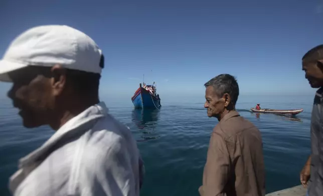 Acehnese men inspect a boat carrying Rohingya refugees anchored in the waters near the coast of Labuhan Haji, Aceh province, Indonesia, Tuesday, Oct. 22, 2024. (AP Photo/Binsar Bakkara)