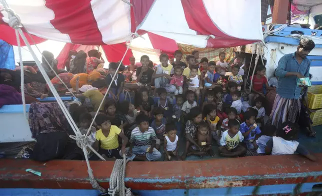 Rohingya children wait for food supply delivered by local fishermen on their boat anchored in the waters near the coast of Labuhan Haji, Aceh province, Indonesia, Tuesday, Oct. 22, 2024. (AP Photo/Binsar Bakkara)